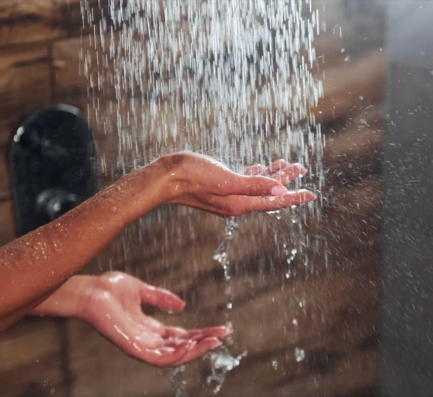 Manos bajo el chorro de agua caliente de la ducha