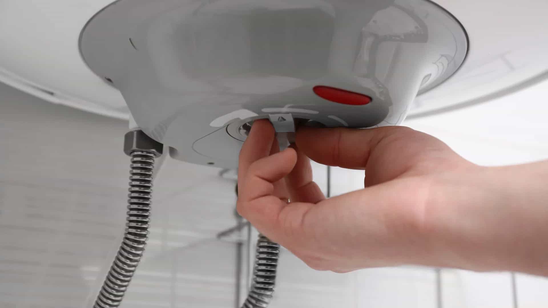 Mano ajustando el termostato de un termo eléctrico