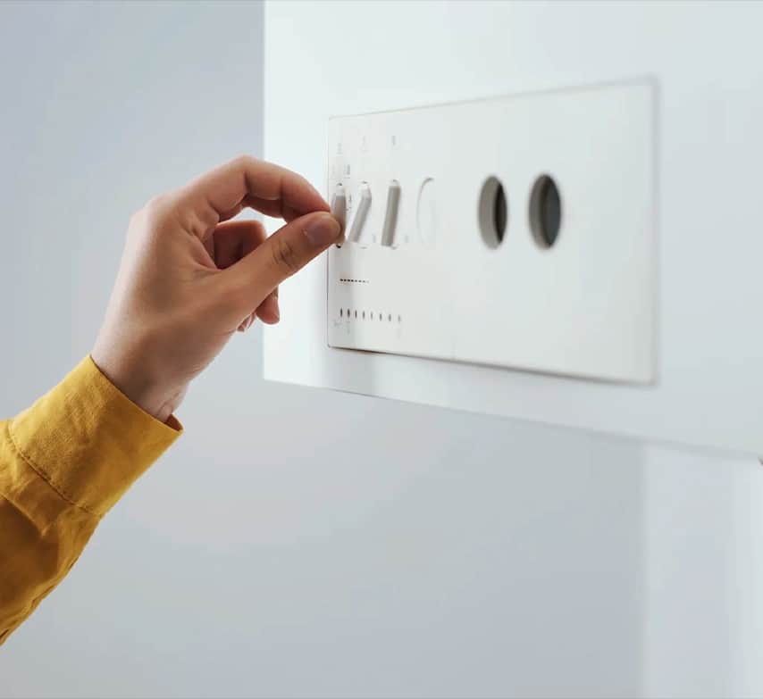 Mano accionando los mandos de un calentador de pared
