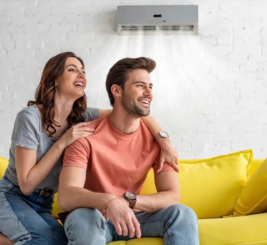 Pareja sonriendo en el salón bajo un aire acondicionado split