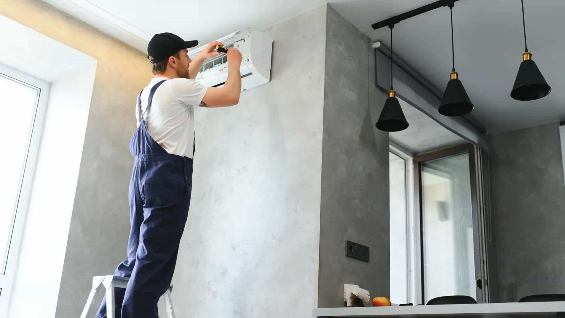 Técnico revisando un aire acondicionado split subido a una escalera