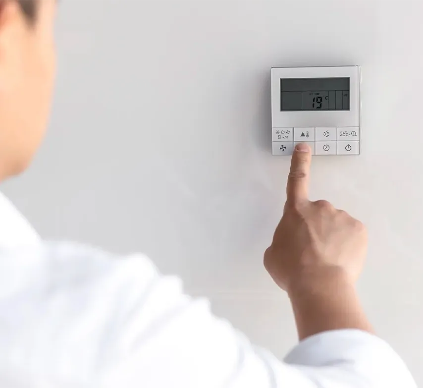 Dedo pulsando un termostato de pared para ajustar la temperatura de la calefacción